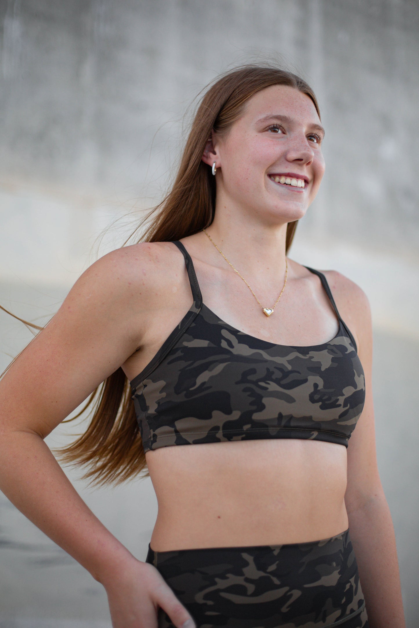 Woman wearing a camouflage sports bra and leggings against a neutral background