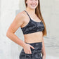 Person wearing a sports bra and leggings set against a concrete wall.