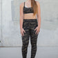 Person wearing camouflage athletic wear standing against a concrete wall.